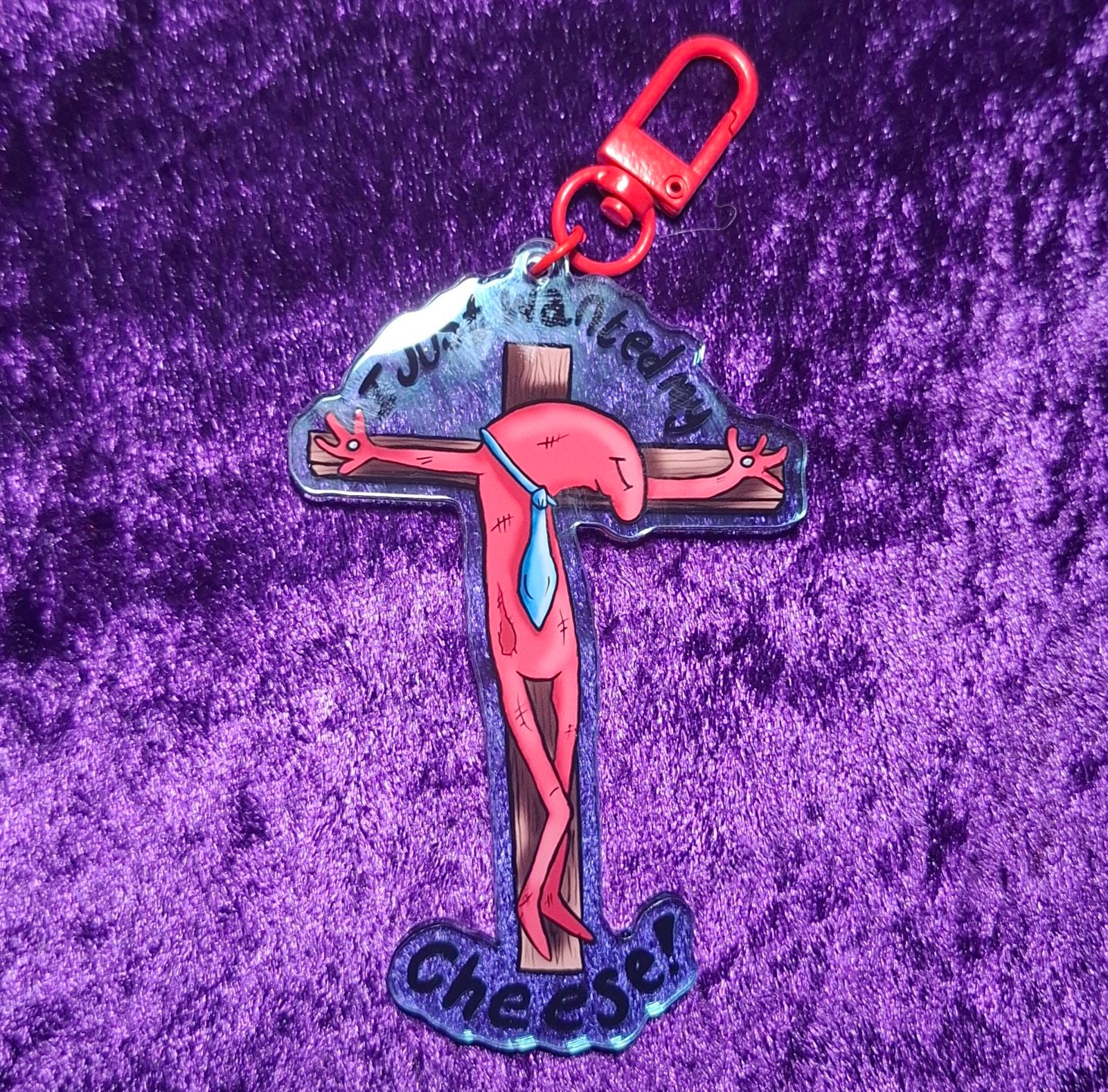 Cross-shaped keychain with a character design on a purple textured background