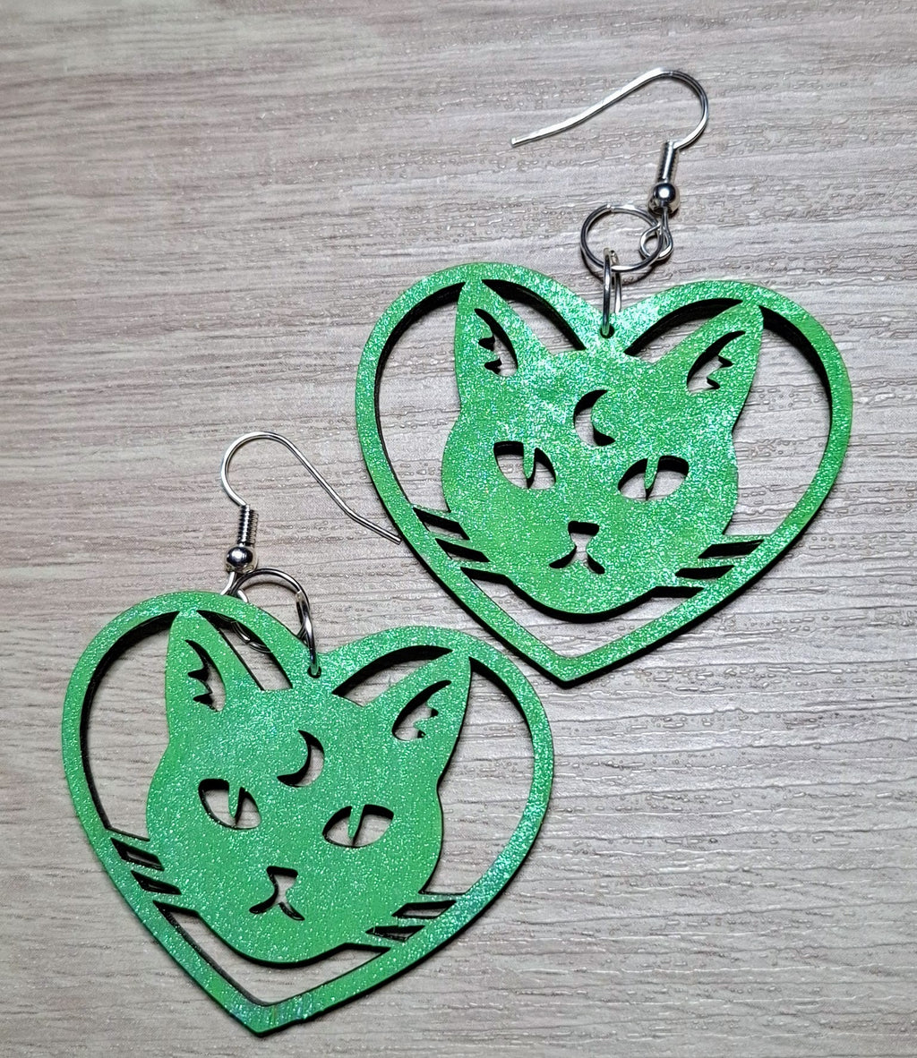 Green cat-shaped earrings on a wooden surface