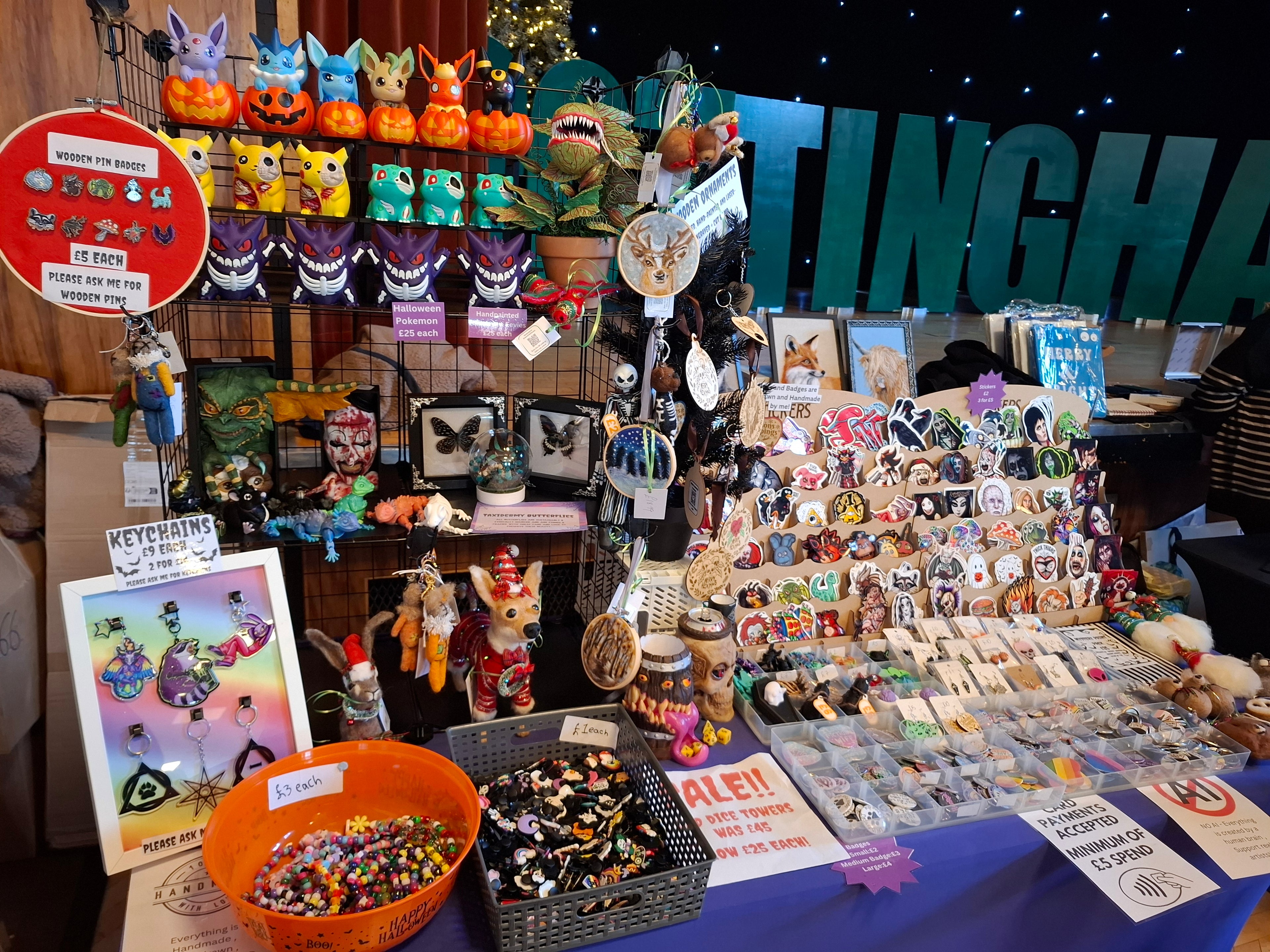 Table display with various small figurines, keychains, and other items at a convention.