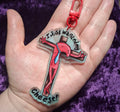 Keychain with cartoon character and text held in a hand against a purple background